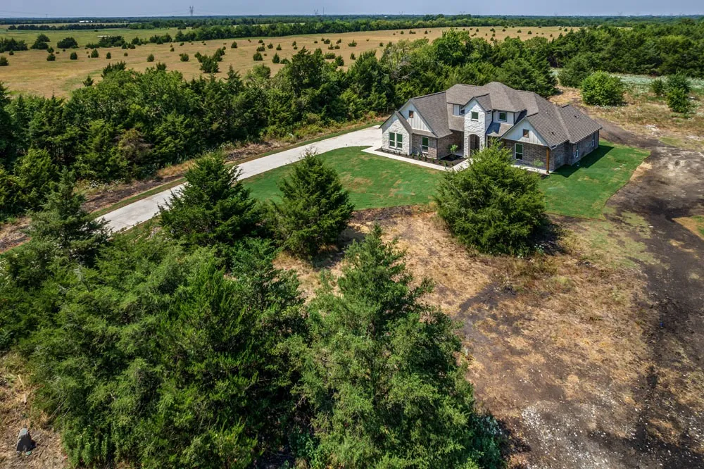 Aerial view of a completed home and surrounding land
