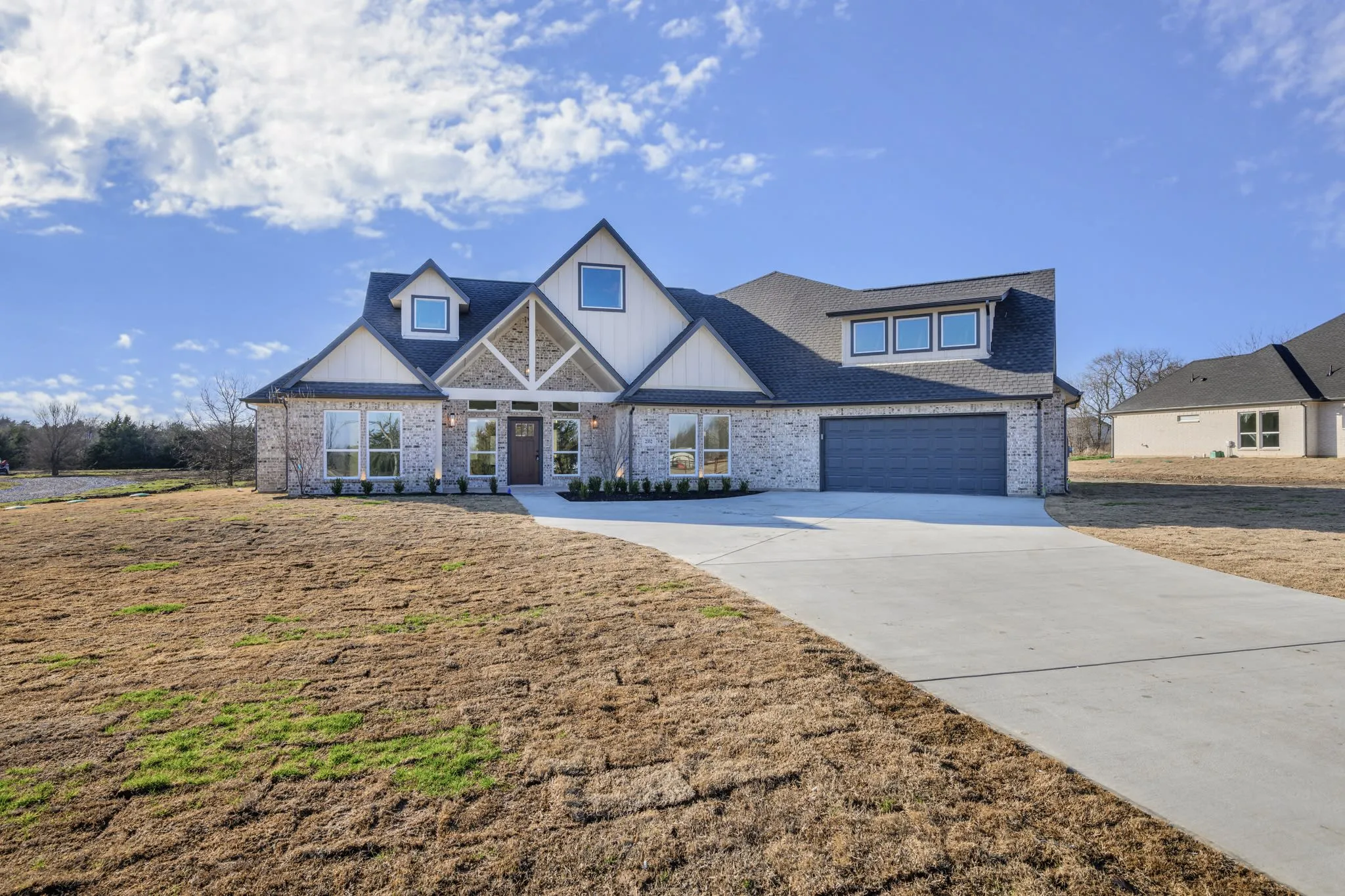 White and stone two-story custom home with a broad driveway