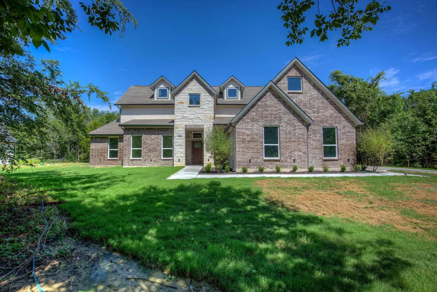Brick and stone custom home framed by mature trees in Terrell